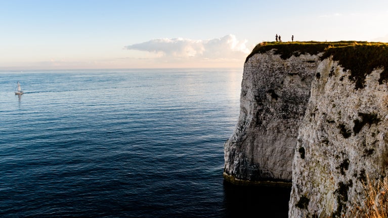 View of the chalk cliffs at Old Harry Rocks with walkers on the cliff s